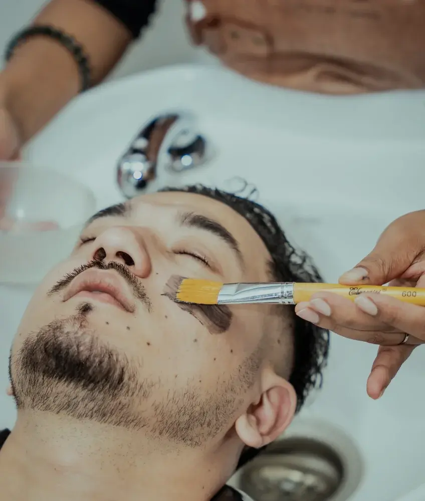 Barber putting on a black mask on a customer